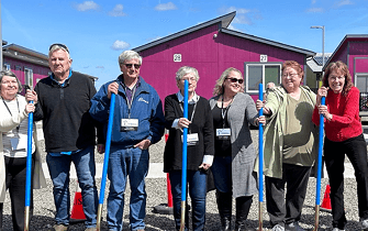 Group of older people holding gardening tools and smiling at the camera
